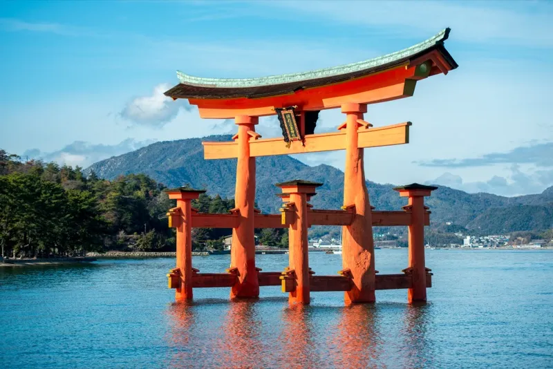 The ryōbu torii of Itsukushima Shrine standing in the Seto Inland Sea — four bracing pillars support the main columns