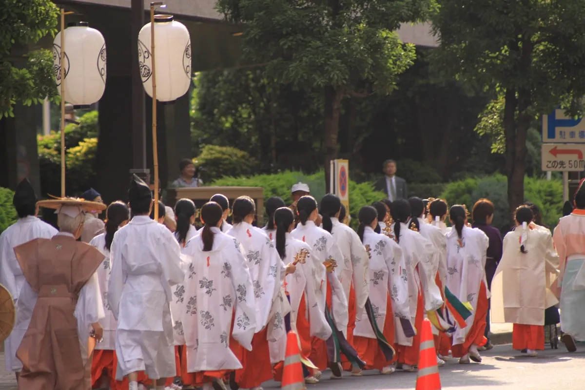 東京の御神輿行列。白い装束の担ぎ手たちが御神輿を高く担ぎ上げ、街中を練り歩く